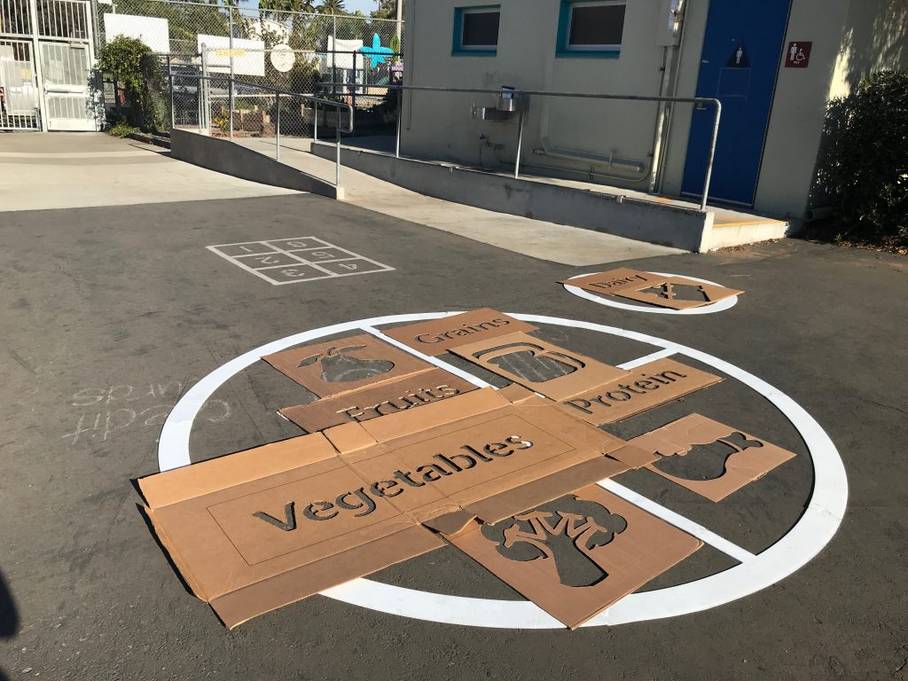 cardboard words and vegetables laid out on cement