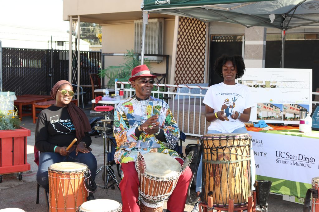 3 people sitting in front of drums