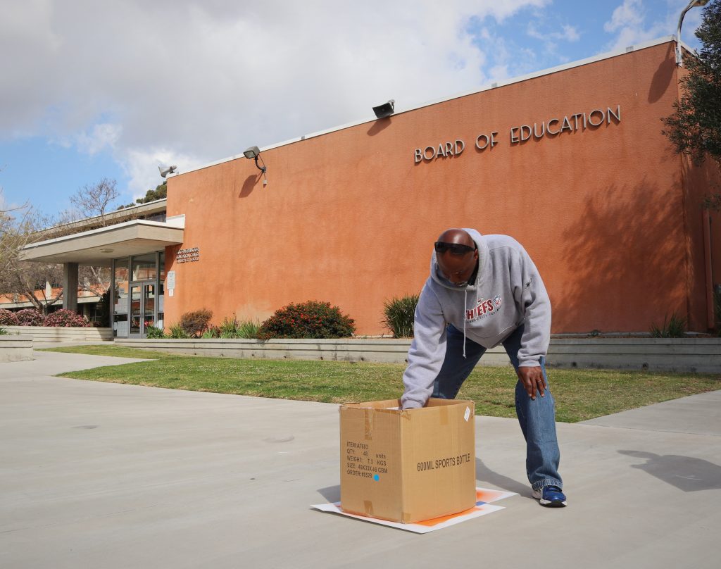 person spray painting sign in box