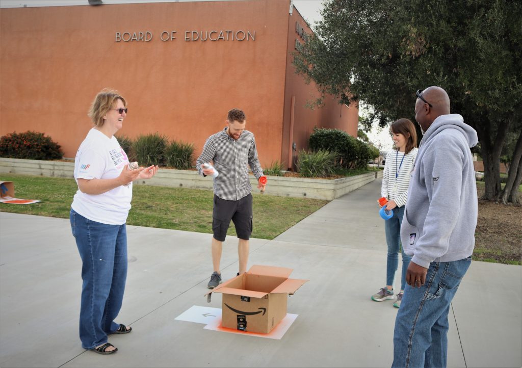 people standing around spray painted box