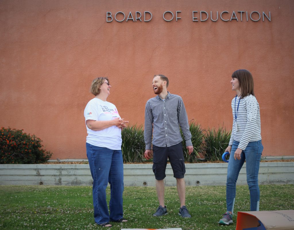 three people in front of the board of education