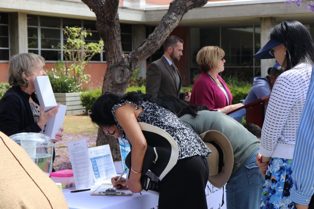 person filling out form on clipboard at table