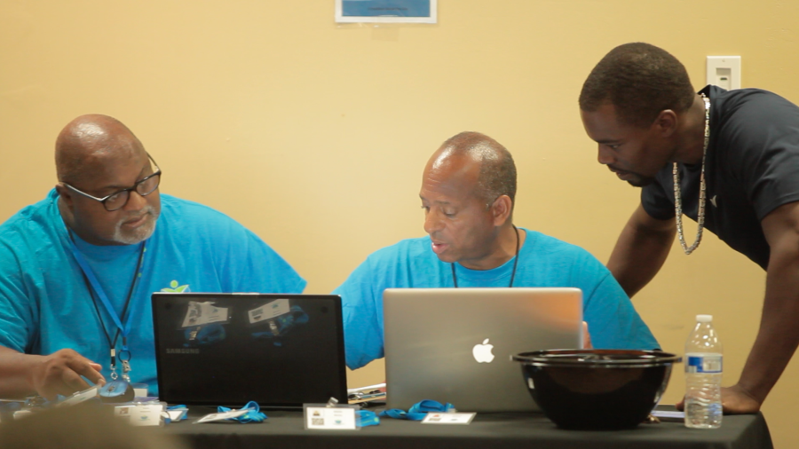 three people looking and talking over 2 laptops